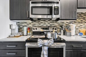 A modern kitchen with a stainless steel microwave, oven, and stovetop. - 5 Mins to Broadway. Midtown. Pool. Gym. Downtown (Nashville)