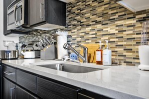 A modern kitchen with a stainless steel sink, a kettle, and a knife block. - 5 Mins to Broadway. Midtown. Pool. Gym. Downtown (Nashville)
