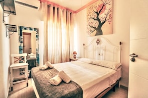 A bedroom with a bed, a nightstand, a chair, a painting, and a window with curtains. - Patina | Local Charm By The Sea | La Cala Beach (Las Lagunas de Mijas)