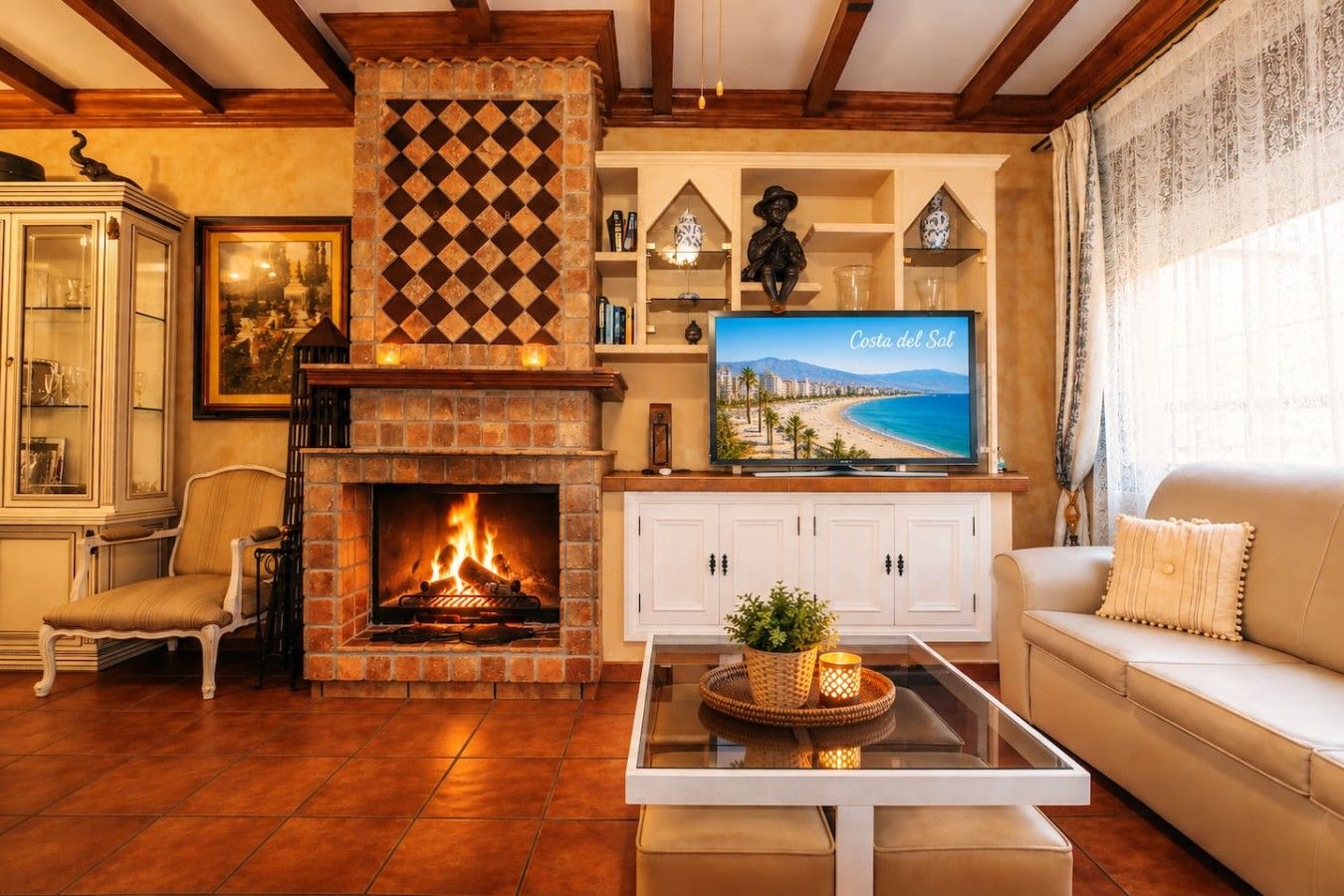 A living room with a fireplace, a television displaying Costa del Sol, and a sofa.
