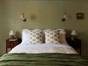 A neatly made bed with floral pillows, two bedside lamps, and a framed picture on the wall. - Charming Two Bedroom Cottage in Malmesbury (Malmesbury)