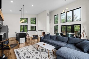 Ein modernes Wohnzimmer mit einer Eckcouch, einem kleinen Couchtisch und einem Essbereich mit Tisch und Stühlen.