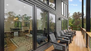 A modern house with large windows, a deck with outdoor furniture, and a visible backyard.