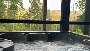 Un bain à remous avec vue sur un paysage boisé, grâce à de grandes fenêtres.
