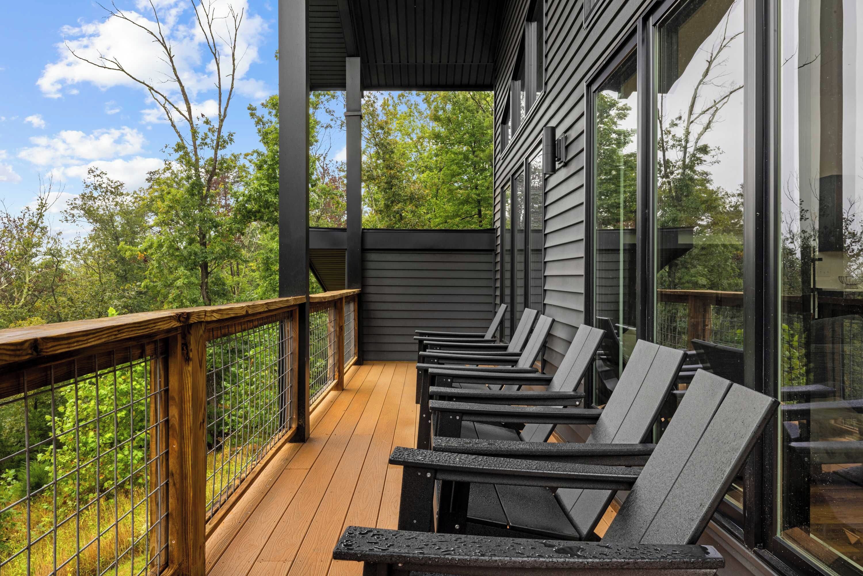 A covered outdoor deck with wooden railings and multiple lounge chairs.