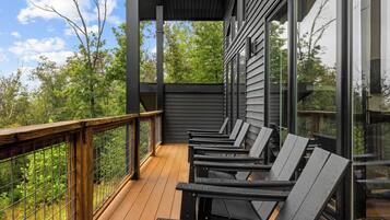 A covered outdoor deck with wooden railings and multiple lounge chairs.