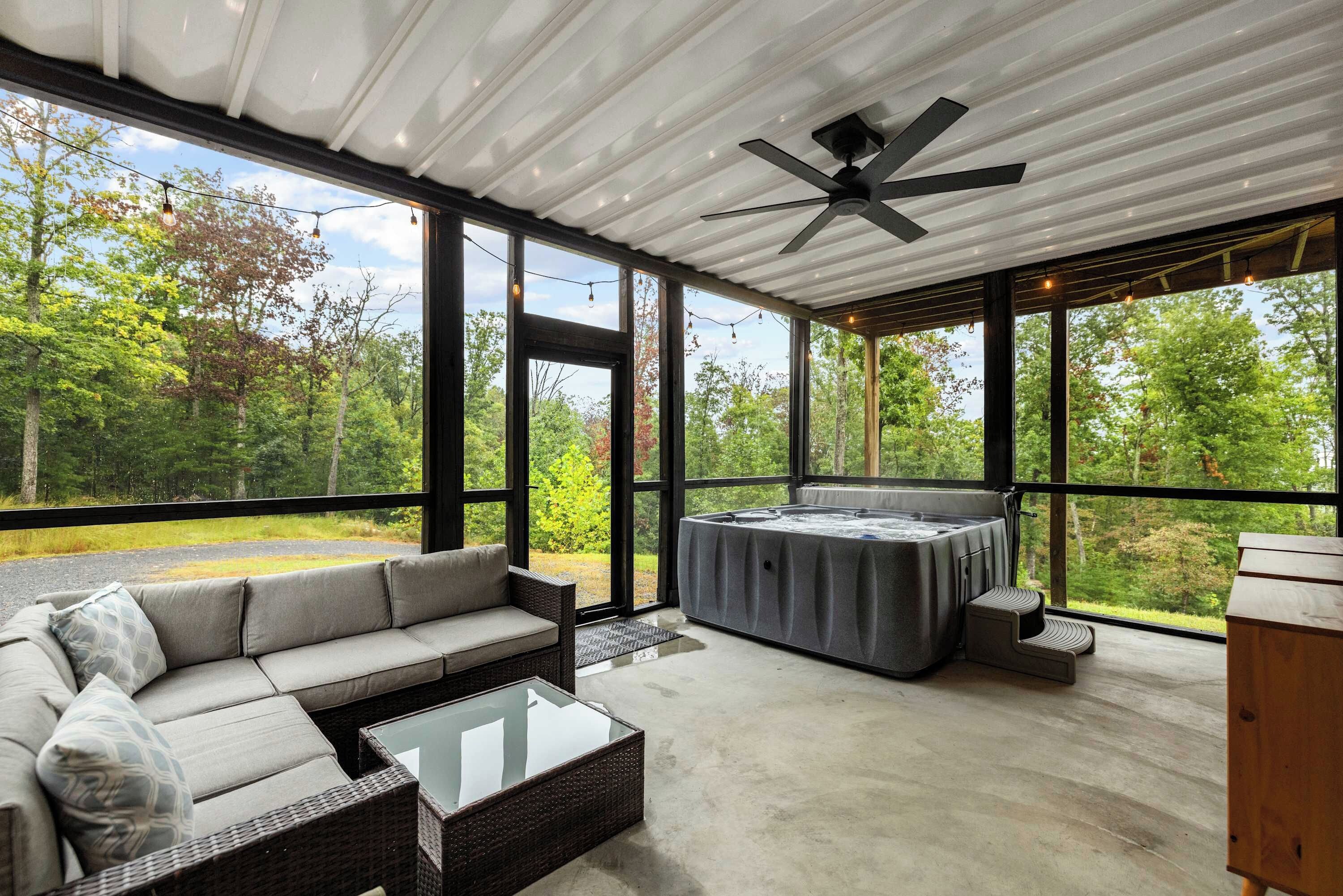 Ein geräumiges Zimmer mit großem Fenster, Deckenventilator, einer Couch, einem Tisch und einer Whirlpool-Badewanne.