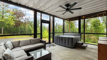 Ein geräumiges Zimmer mit großem Fenster, Deckenventilator, einer Couch, einem Tisch und einer Whirlpool-Badewanne.