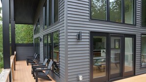 Une maison moderne dotée d’une terrasse, de grandes fenêtres et d’un espace extérieur couvert avec des sièges.