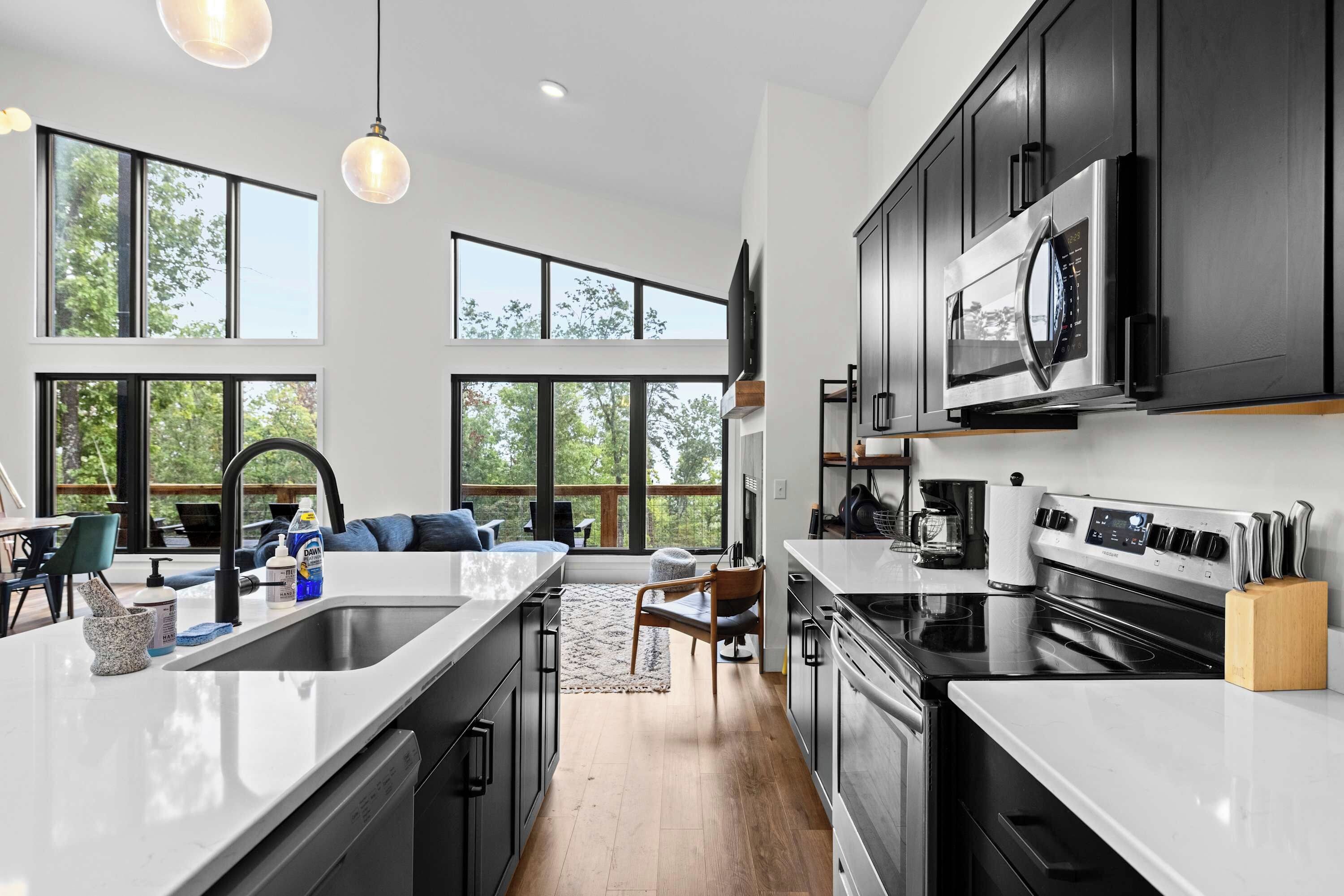 A modern kitchen with a central island, stainless steel appliances, and large windows.