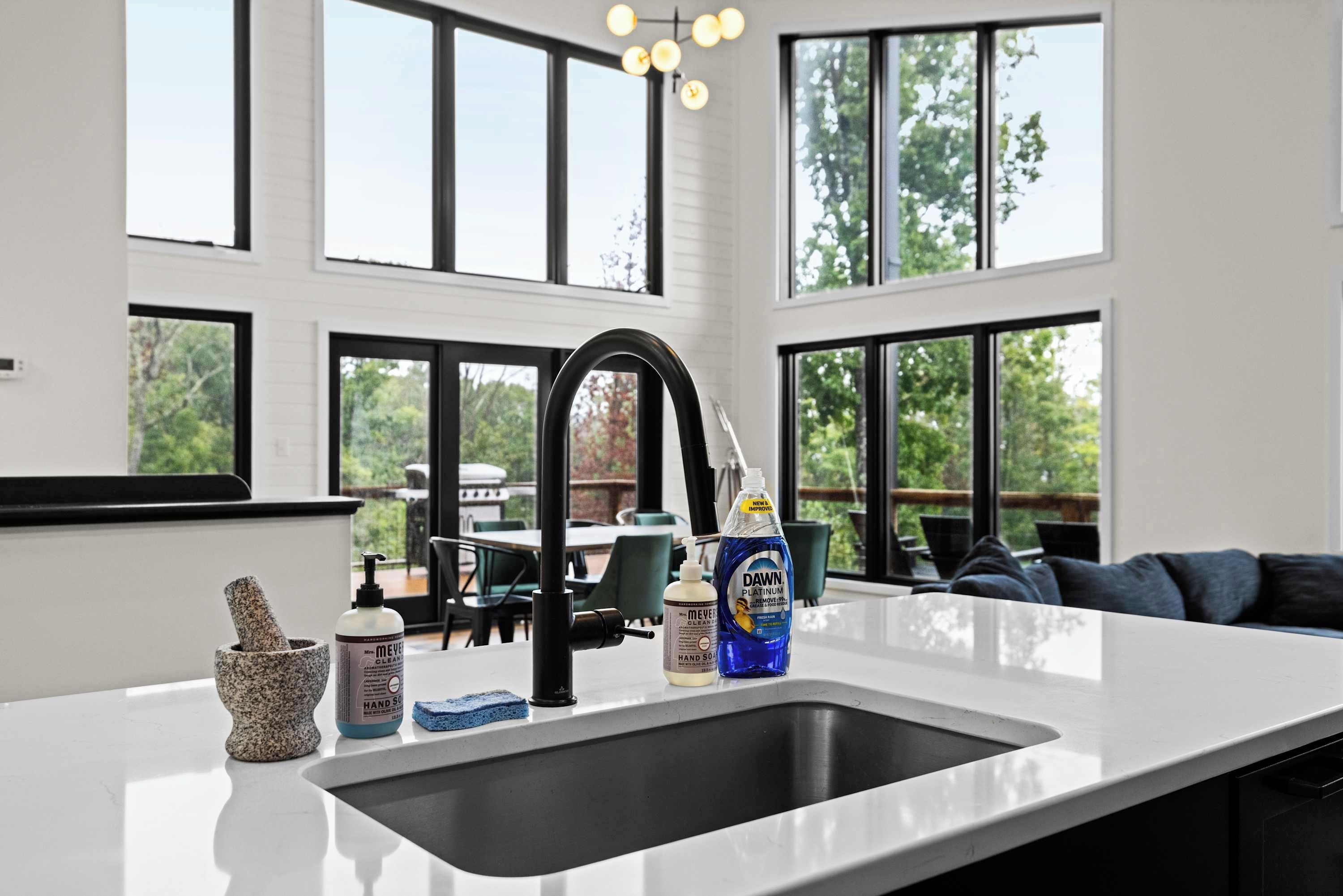A modern kitchen with a large sink, a stone mortar and pestle, and hand soap.