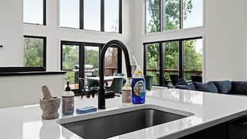A modern kitchen with a large sink, a stone mortar and pestle, and hand soap.