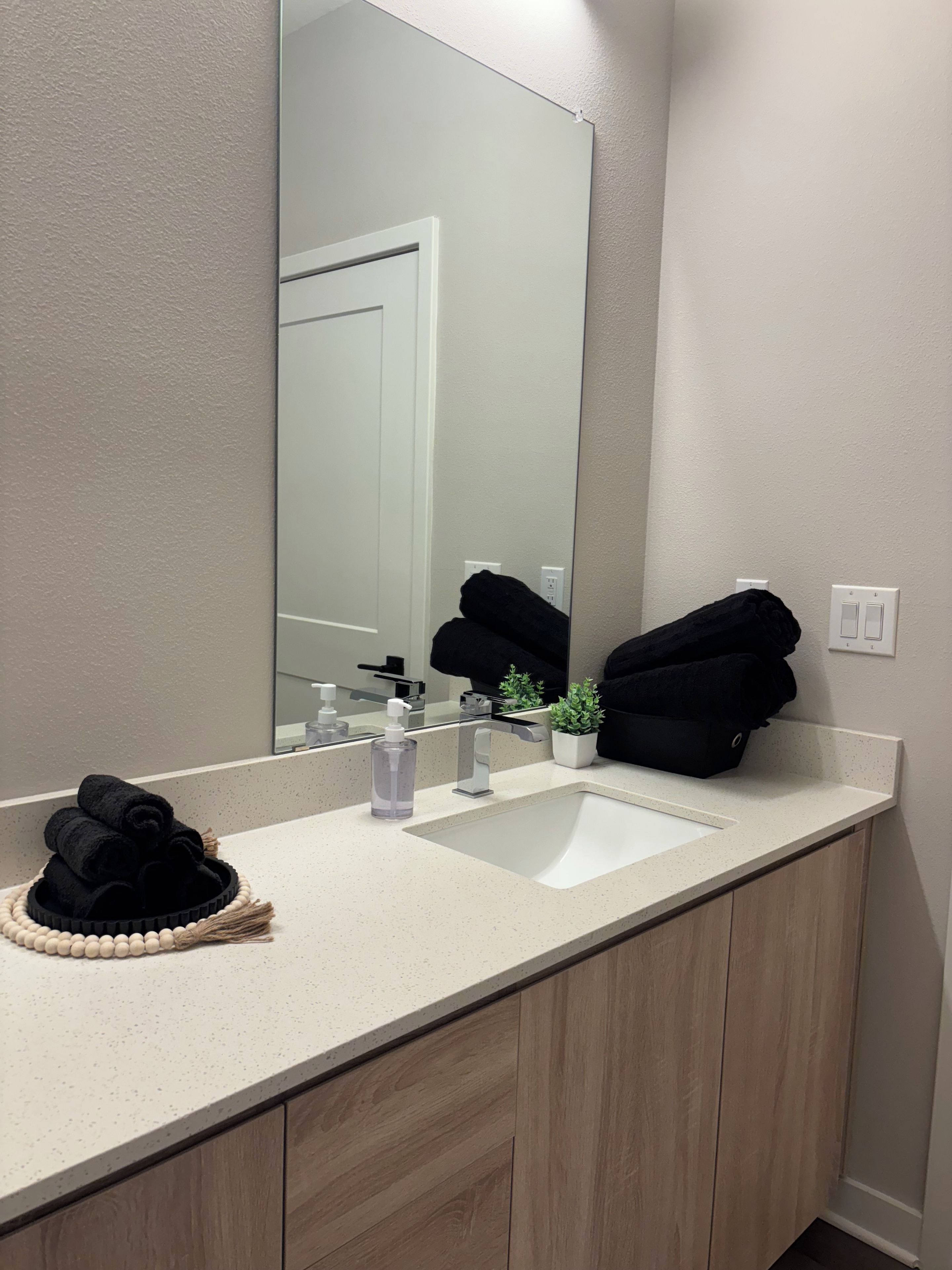 A bathroom with a white sink, a mirror, and a towel rack with towels.