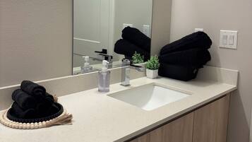 A bathroom with a white sink, a mirror, and a towel rack with towels.