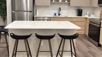 A modern kitchen with a central island, stainless steel appliances, and pendant lighting.