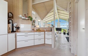 Eine moderne Küche mit weißen Schränken, einer Holz Arbeitsplatte und einem großen Fenster mit Blick ins Freie.