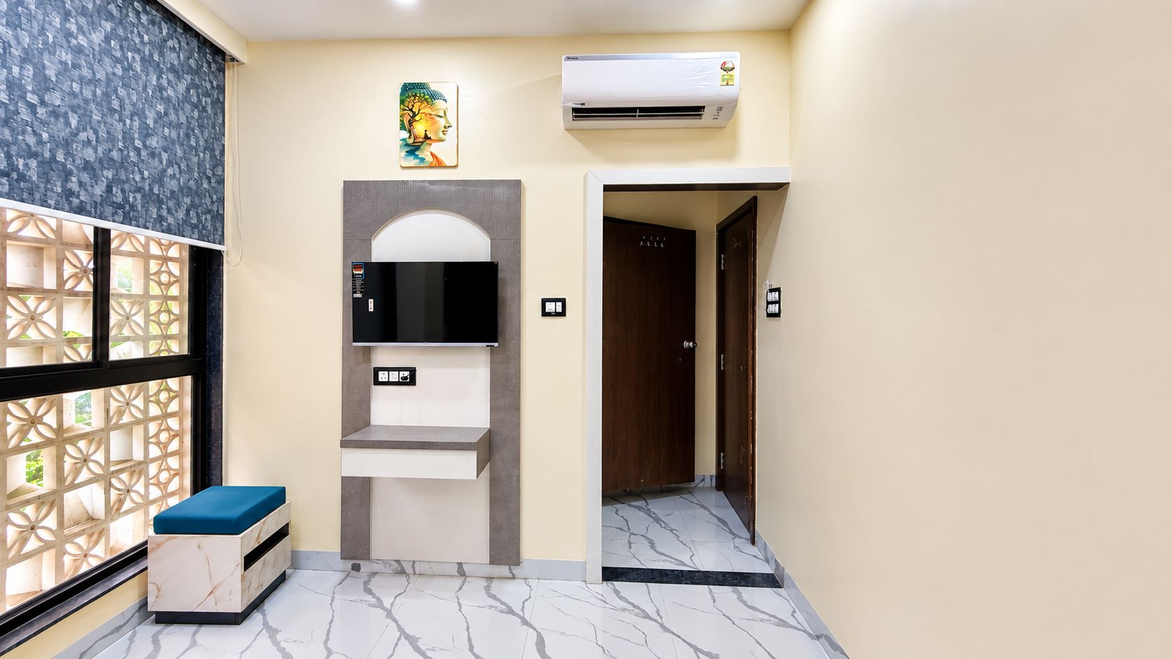 A hotel room with a marble floor, a built-in TV, a small seating area, and a decorative wall piece.