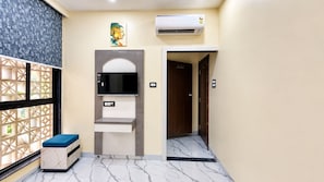 A hotel room with a marble floor, a built-in TV, a small seating area, and a decorative wall piece. - Hotel B-1 (Indore)
