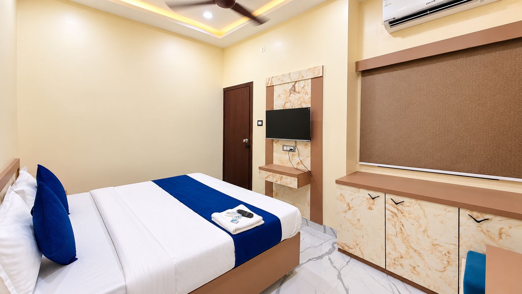 Une chambre d’hôtel équipée d’un lit, d’une télévision, d’une armoire et d’un ventilateur de plafond.
