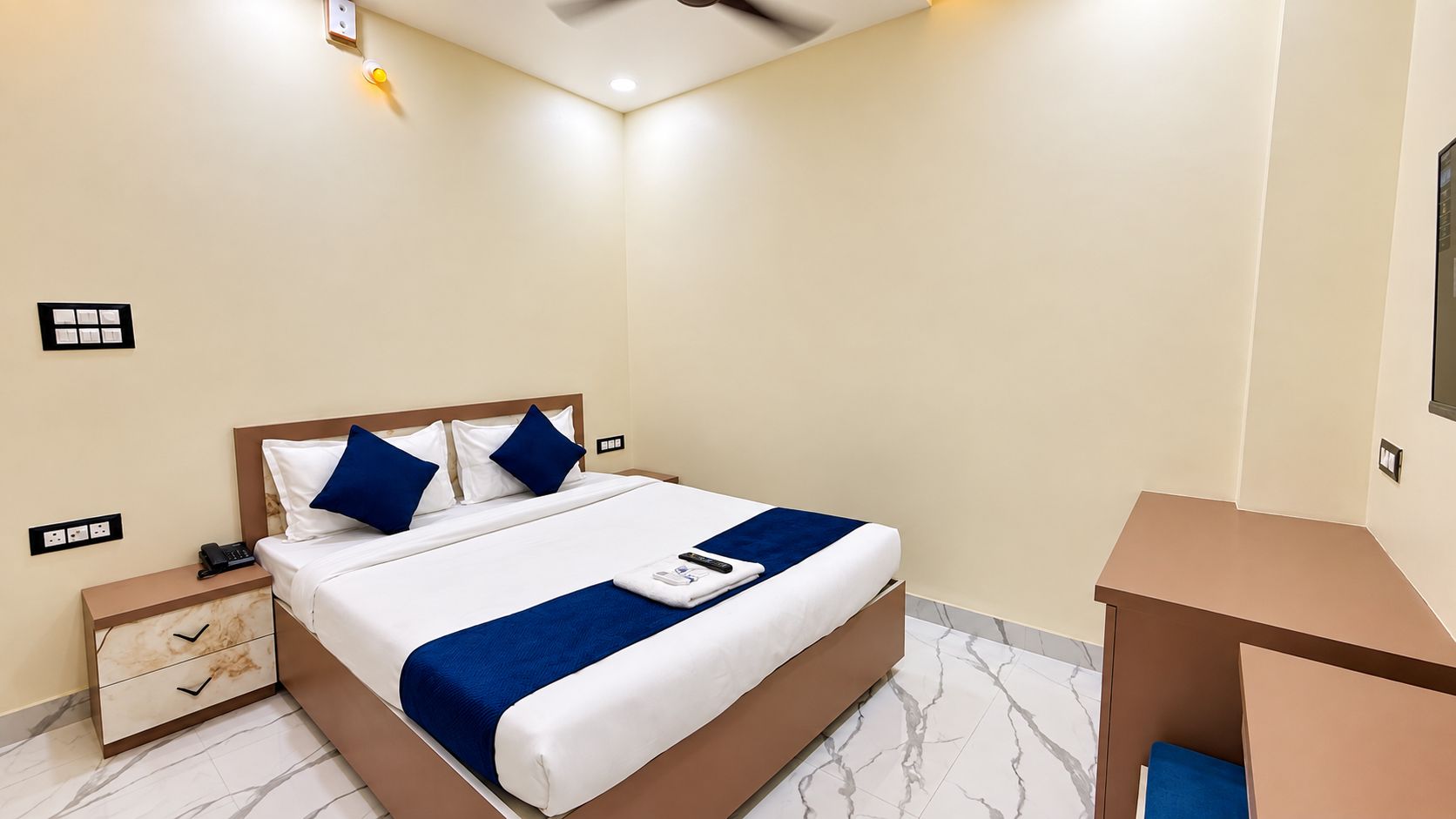 Una camera d'albergo con un letto, un comodino e una piccola scrivania.