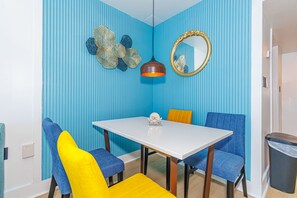 A dining area with a white table, blue chairs, and a yellow cushion. - Endless Ocean Views at Yachtsman S904 (Myrtle Beach)