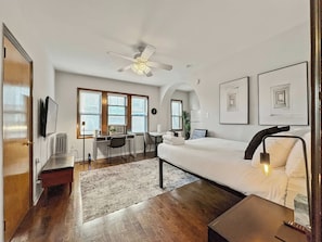 Quarto de hotel moderno com cama, escrivaninha e área de estar.