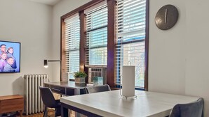 Un espace repas moderne comprenant une table, des chaises, une horloge et un radiateur.
