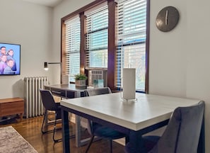 Uma área de jantar moderna com mesa, cadeiras, um relógio e um radiador.