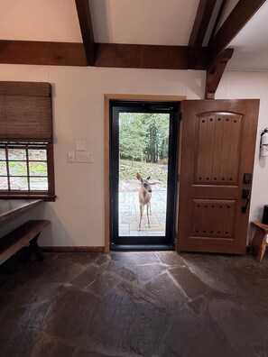 A room with a stone floor, a wooden bench, a door leading outside, and a wall-mounted light fixture. - Rustic Elegance Wrapped in Nature!   

3-bedroom Cabin in Serene Lake Harmony (Lake Harmony)