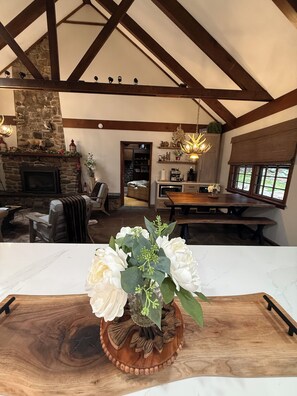 A spacious living area with a stone fireplace, wooden beams, and a dining table. - Rustic Elegance Wrapped in Nature!   

3-bedroom Cabin in Serene Lake Harmony (Lake Harmony)