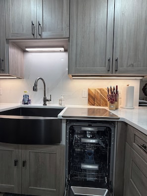 A kitchen with a stainless steel sink, wooden cabinets, and a dishwasher. - Rustic Elegance Wrapped in Nature!   

3-bedroom Cabin in Serene Lake Harmony (Lake Harmony)