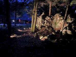 A forested area with a stone wall and a building in the background. - Rustic Elegance Wrapped in Nature!   

3-bedroom Cabin in Serene Lake Harmony (Lake Harmony)