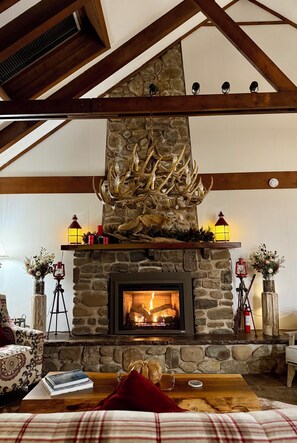 A stone fireplace with a fire, wooden beams, and a rustic decor. - Rustic Elegance Wrapped in Nature!   

3-bedroom Cabin in Serene Lake Harmony (Lake Harmony)