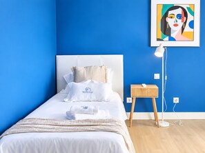 Ein Hotelzimmer mit Bett, Nachttisch, Lampe und einem Gemälde an der Wand.