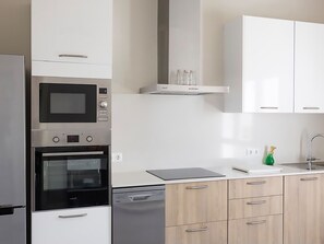 Eine moderne Küche mit Edelstahlgeräten, Holzschränken und einem eingebauten Geschirrspüler.
