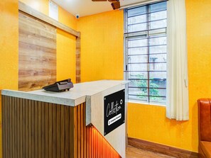 A reception desk with a sign, a window with a view, and a wooden wall. - Super Collection O Six Mile Guwahati (Guwahati)