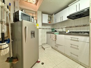 Eine Küche mit Kühlschrank, Mikrowelle und Herd. Es gibt Schränke und ein Spülbecken.