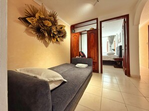 A room with a bed, a sofa, a decorative wall piece, and a door leading to another room. - Spacious 3-bedroom apartment near Zona T, a charming neighborhood (Bogotá)