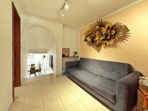 A living room with a grey sofa, a decorative wall piece, and a tiled floor. - Spacious 3-bedroom apartment near Zona T, a charming neighborhood (Bogotá)