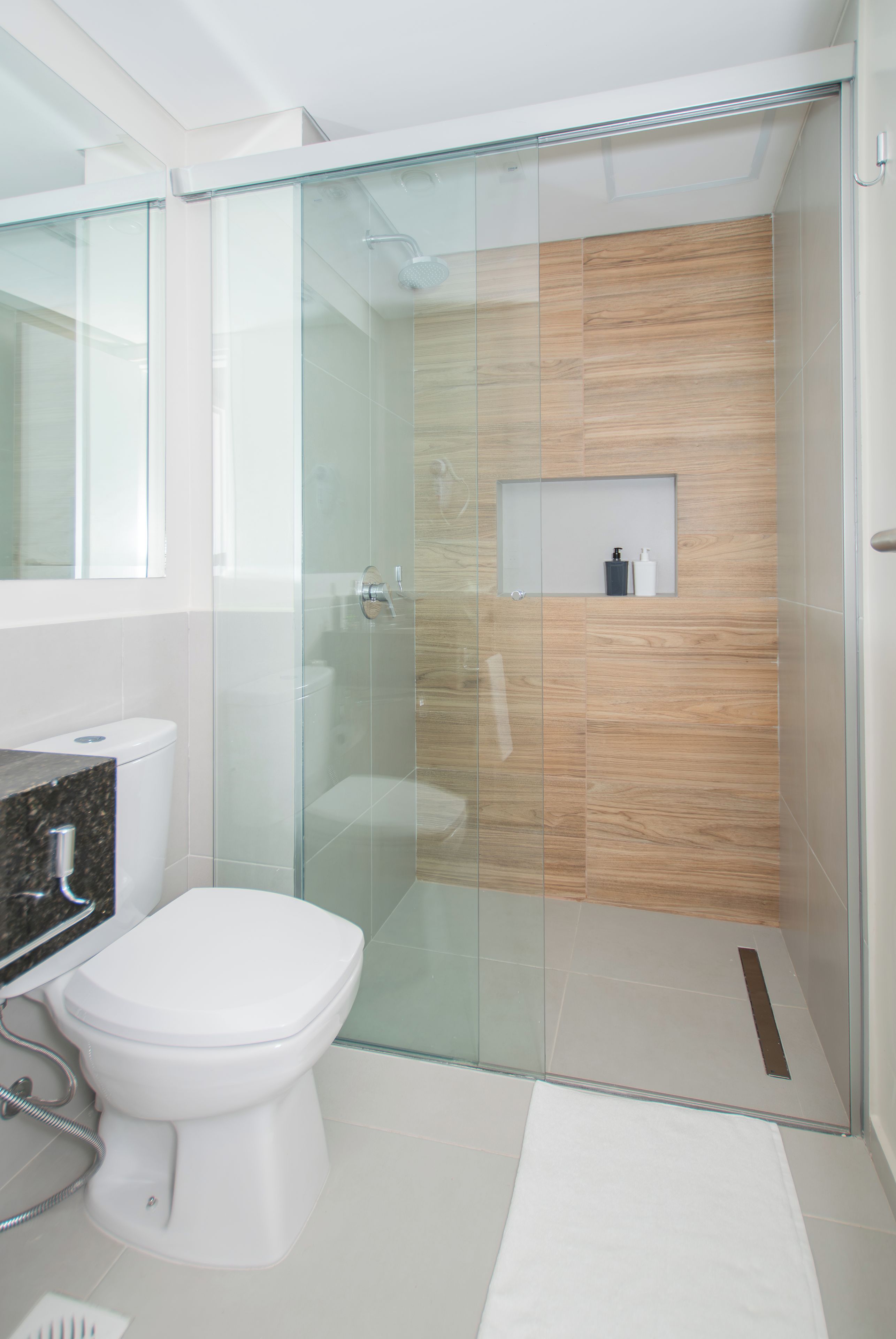 Un baño moderno con cabina de ducha de vidrio, inodoro y tocador con espejo.