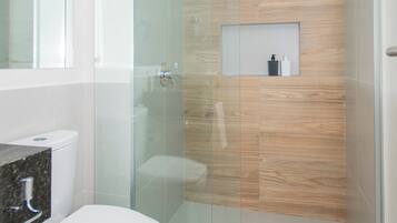 Un baño moderno con cabina de ducha de vidrio, inodoro y tocador con espejo.