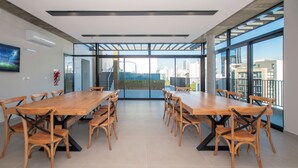A conference room with a long table and chairs, large windows, and a view of the cityscape. - Corporate Stays First del Sol - 707 (Asunción)