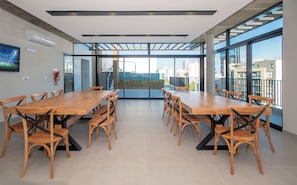 A conference room with a long table and chairs, large windows, and a view of the cityscape. - Corporate Stays First del Sol - 707 (Asunción)