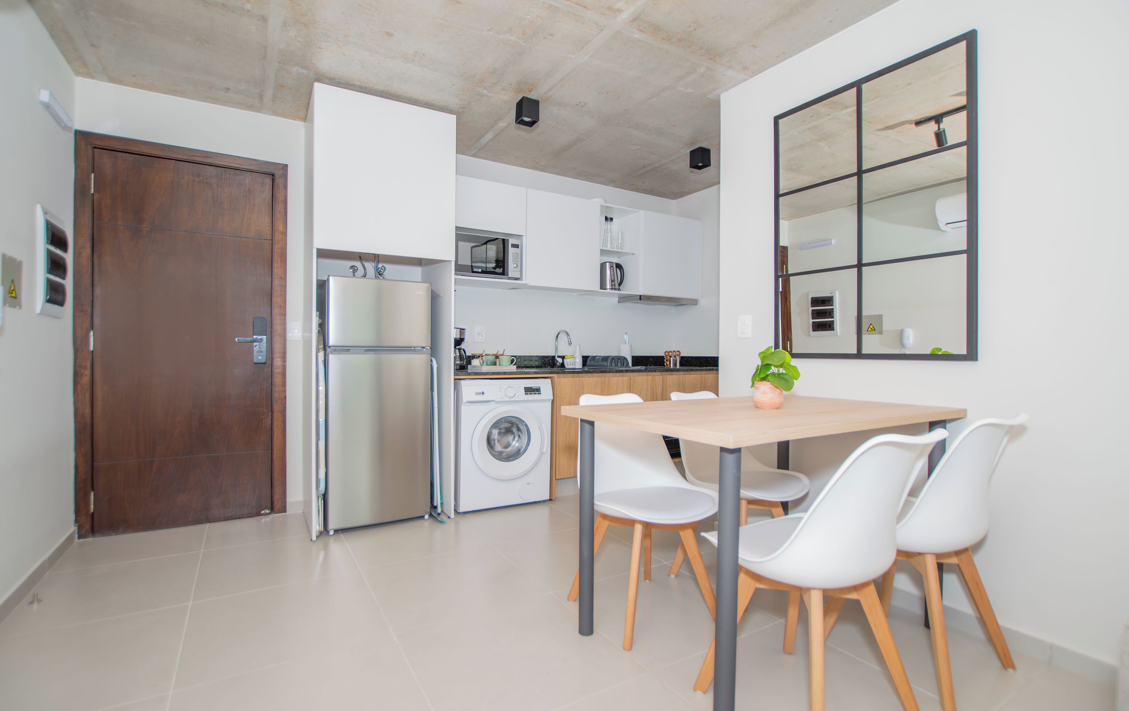 Cocina compacta con lavadora, refrigerador y comedor con sillas y mesa.