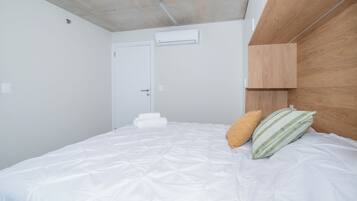 Un dormitorio con una cama, almohadas, un cabecero de madera y una puerta blanca.