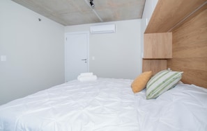 A bedroom with a bed, pillows, a wooden headboard, and a white door. - Corporate Stays First del Sol - 707 (Asunción)