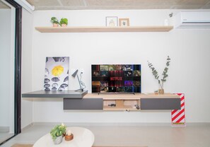 A modern living room with a flat-screen TV mounted on a wall, a coffee table with decorative items, and a small plant. - Corporate Stays First del Sol - 707 (Asunción)