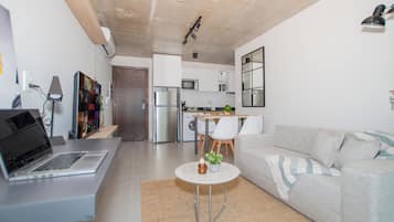 Una sala de estar moderna con un sofá, una mesa de centro y una computadora portátil sobre un escritorio.