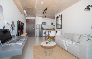 Una sala de estar moderna con un sofá, una mesa de centro y una computadora portátil sobre un escritorio.