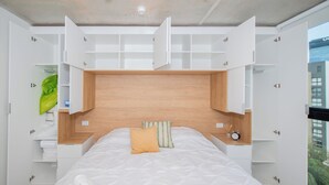 A bedroom with a bed, built-in shelving, and a view of the outside. - Corporate Stays First del Sol - 707 (Asunción)
